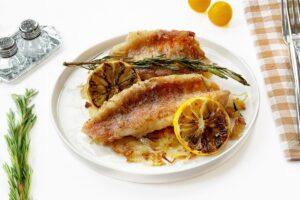 Fried sea bass with onions in a frying pan